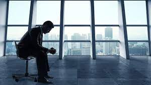 a man sitting in a chair in a room with a view of a city