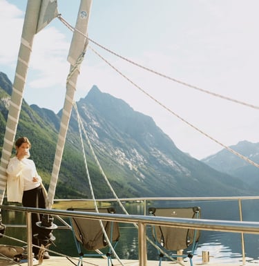 Georgina Amorós on sailboat deck with scenic mountain backdrop during summer sailing in Lofoten