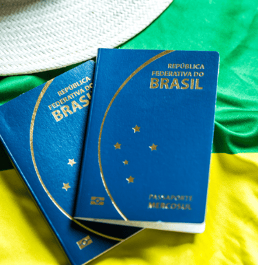 dois passaportes brasileiros en frente de uma bandera brasileira