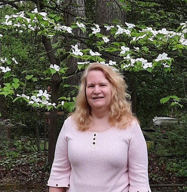 Claudia Smarkola, healer and coach, standing in front of a dogwood tree