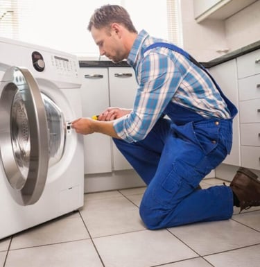 a man in overalls and overalls is fixing a washing machine