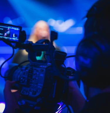 Professional videographer filming a live event with a Sony 4K cinema camera in a studio with blue lighting.