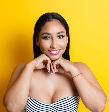 Smiling woman in her 30s and long dark hair posing against a vibrant yellow background.
