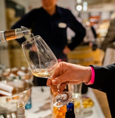 Hand of a wine professional holding out a glass which is being poured full of wine