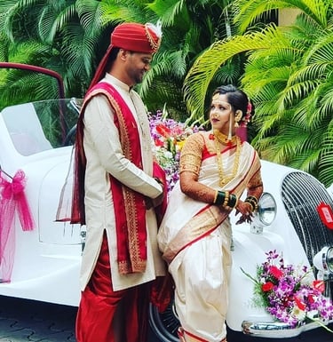 a man and woman in traditional indian attire standing in front of a car