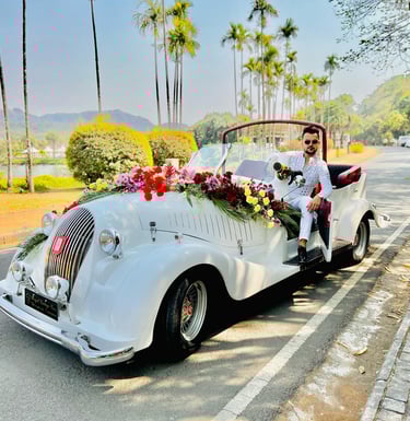 a man in a white suit and tie is sitting in a convertible car