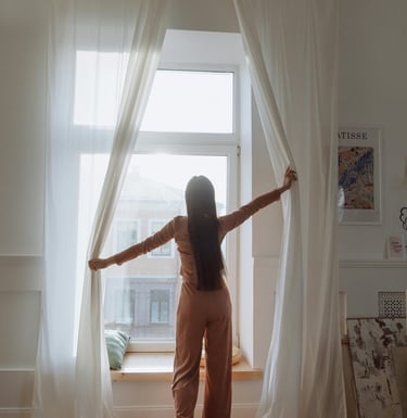 Women opening the day curtains letting the light into the room