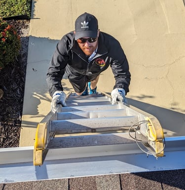 Ryan climbing a ladder to clean a roof vent in SE Cape Coral