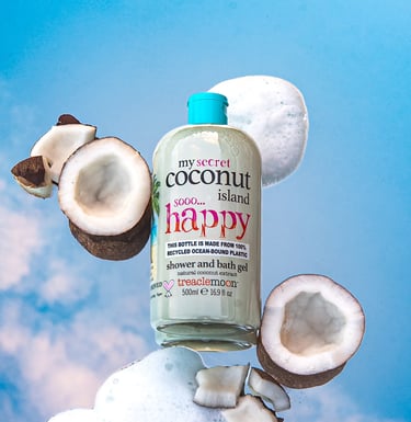 Treaclemoon Coconut Island shower gel styled with coconuts and foam against a blue sky
