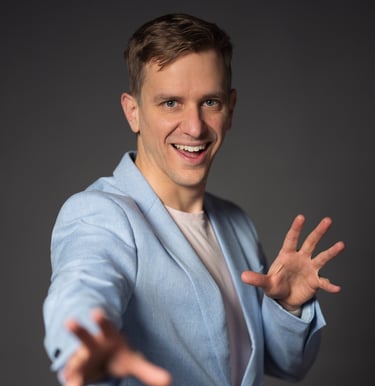 Remy wearing a blue blazer and smiling, hands open to the viewer