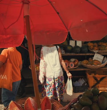 Street market scene under red umbrella showing fruit vendors and shoppers at Port Louis Central Market, Mauritius