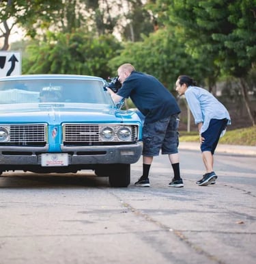 A cameraman and a director filming a classic car