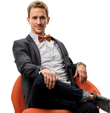 Remy sits in a chair wearing a sportcoat and bowtie