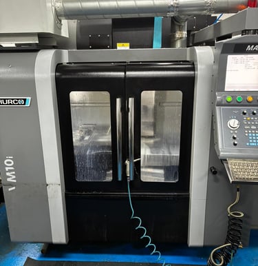 A Hurco VM10i CNC vertical machining center featuring a control panel and sliding safety doors.
