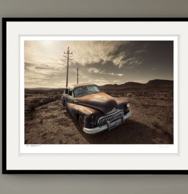Old rusted classic car with telephone poles and mountains in the background