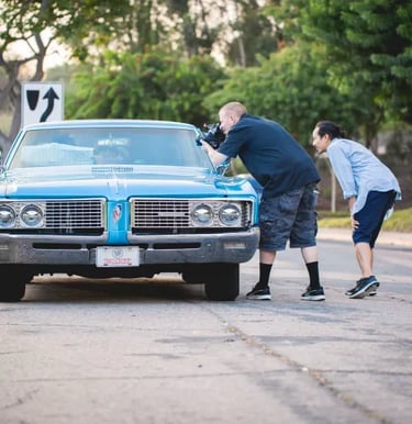 A cameraman and a director filming a classic car