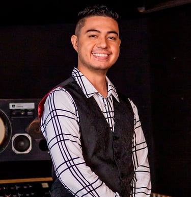 Bassist Ian Yoshio smiling, wearing a white shirt with black stripes and a black vest.