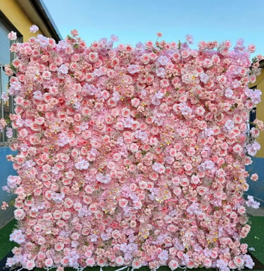 A pink flower wall backdrop featuring artificial roses and cherry blossoms for events.
