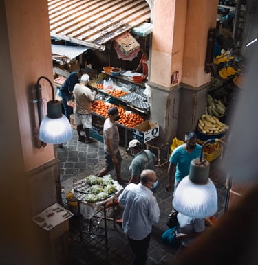 Busy market scene in Mauritius with vendors and customers at fruit and vegetable stalls under warm lighting