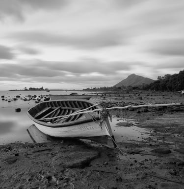 Long exposure shot of a wooden boat on a rocky shoreline at Petite Case Noyale in Mauritius 