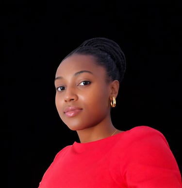 A young woman with braided hair and gold earrings wearing a vibrant red top against a dark background.