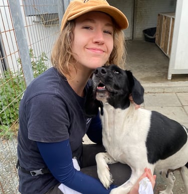 a woman in a hat and a dog sitting on a stool