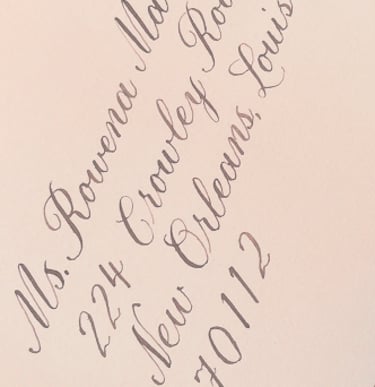 light pink envelope with an address written in calligraphy script in brown ink