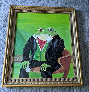 Repainted repurposed canvas and frame. Painting of a toad in a suit sitting on a chair.
