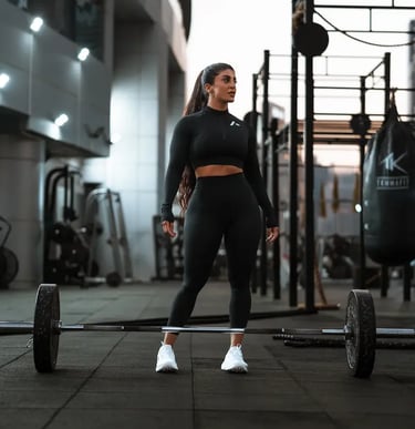 mais alhajarji wearing black sportswear standing in a gym in front of a barbell