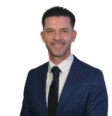 Professional headshot of a smiling businessman in a blue plaid suit and black tie.