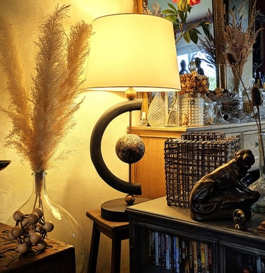 Modern black table lamp with warm glow next to pampas grass and vintage home decor accents.