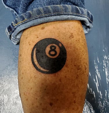 Black 8 ball tattoo on the back of a calf