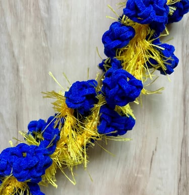 Closeup of royal blue and yellow rosebud leis twisted together