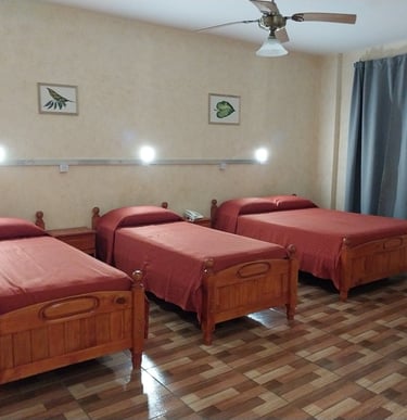 Una habitación con tres camas y un ventilador de techo.