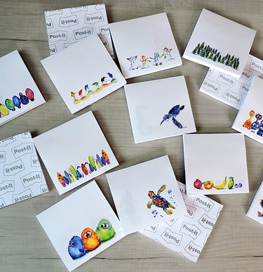Collection of decorative Post-it sticky notes with colorful watercolor illustrations on a wooden surface.