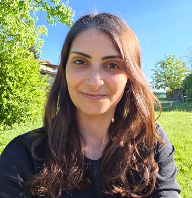 Donna in primo piano che sorride con sfondo di prato e cielo