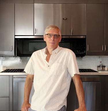 a man standing in a kitchen with a table and chairs