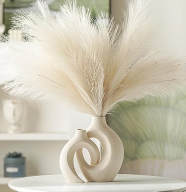 Minimalist beige ceramic donut vase with fluffy artificial pampas grass decor on a white table.