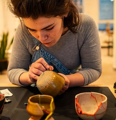 a woman is repairing ceramics with kintsugi reparatur 