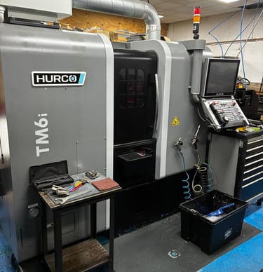 A Hurco TM6i CNC lathe machine in a precision machine shop with industrial tools and control panel.