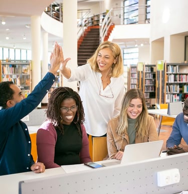 a group of people sitting at a table with laptops
