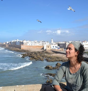 a woman sitting on a ledge looking out over the ocean beatriz alvarez