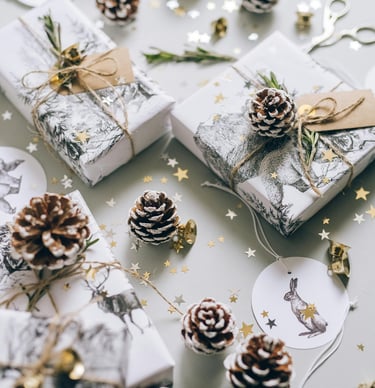Beautifully wrapped Christmas presents with kraft paper, red ribbons, and pine springs.