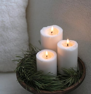 Christmas candles in a wooden tray surrounded by pine branches, creating a warm festive glow