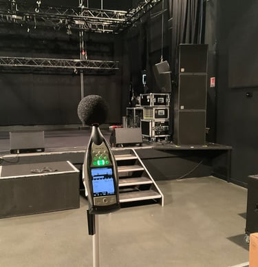 Sonomètre sur un trépied mesurant l'acoustique sur une scène professionnelle avec des enceintes