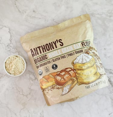 A bag of Anthony's Organic Whole Grain Oat Flour next to a small bowl of finely ground gluten-free flour.