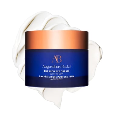 Augustinus Bader The Rich Eye Cream in a blue jar with a copper lid over a thick white cream smear.
