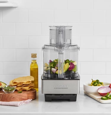 Cuisinart 14-cup food processor on a kitchen counter with fresh salsa ingredients and tortilla chips.