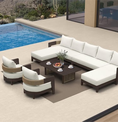 Luxury outdoor patio furniture set with white sectional sofa and armchairs by a blue swimming pool.