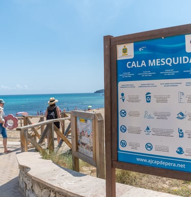 Cala Mesquida beach sign post with the sea in the background